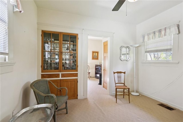 living area with baseboards, carpet, visible vents, and a ceiling fan