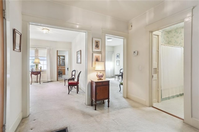 hall featuring light colored carpet and baseboards