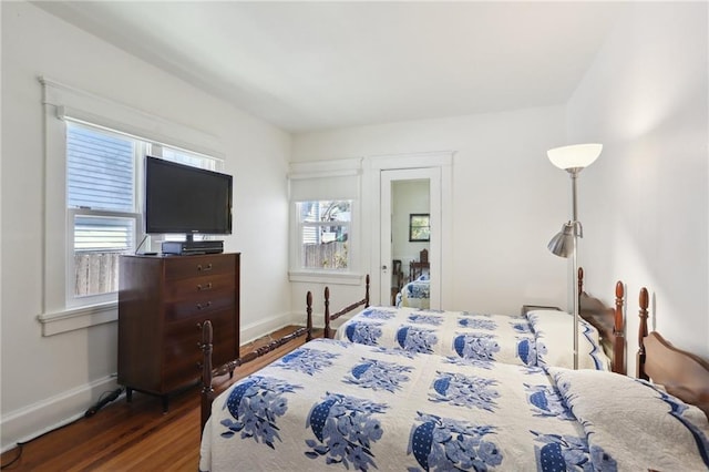 bedroom with multiple windows, baseboards, and wood finished floors