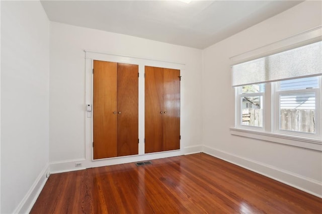 unfurnished bedroom with visible vents, baseboards, and wood finished floors