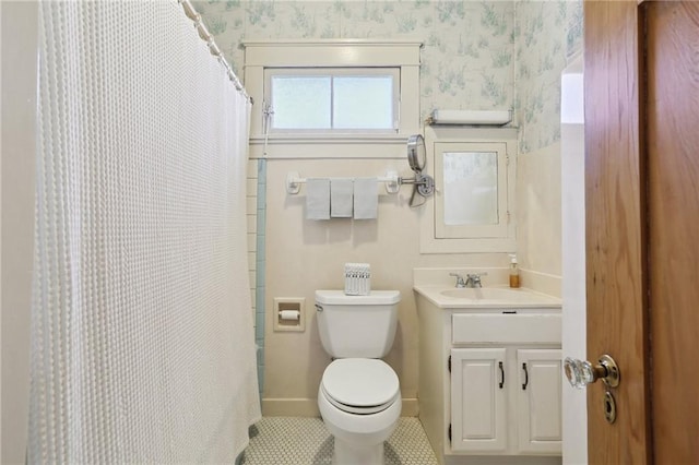 bathroom with toilet, vanity, tile patterned flooring, baseboards, and wallpapered walls