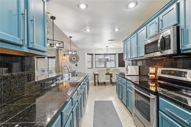 kitchen featuring light tile patterned floors, stainless steel appliances, a sink, blue cabinetry, and decorative backsplash