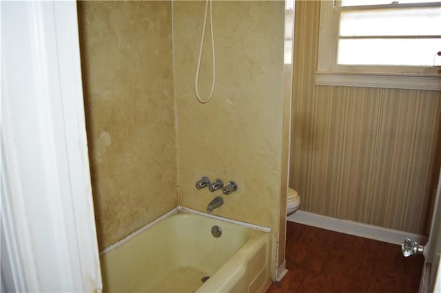 bathroom with wood finished floors, baseboards, toilet, and shower / bathtub combination