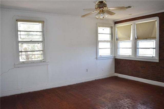 spare room featuring brick wall, wood finished floors, a ceiling fan, and baseboards