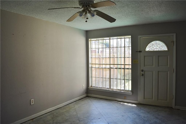 entryway with a ceiling fan, plenty of natural light, baseboards, and a textured ceiling