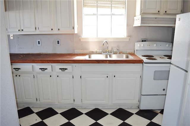 kitchen featuring light floors, wooden counters, white appliances, and a sink