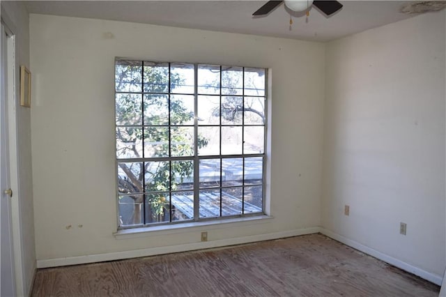 spare room featuring baseboards, a wealth of natural light, and wood finished floors