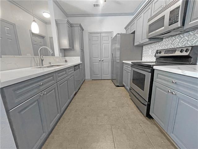 kitchen with a sink, appliances with stainless steel finishes, gray cabinets, tasteful backsplash, and crown molding