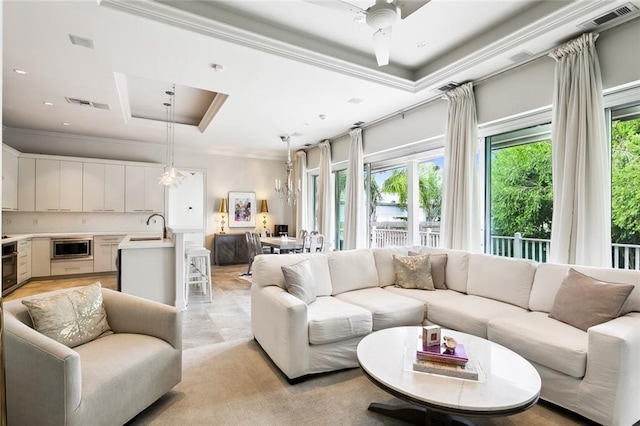 living room featuring a raised ceiling, crown molding, and visible vents