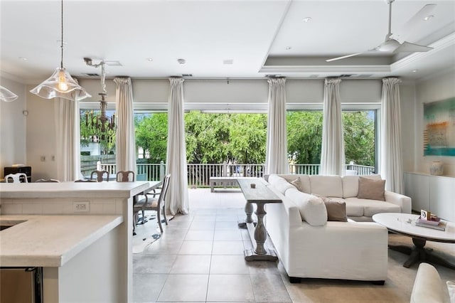 living area featuring a wealth of natural light, crown molding, a tray ceiling, and light tile patterned flooring