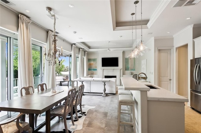 dining area with a tray ceiling, visible vents, a fireplace, and crown molding