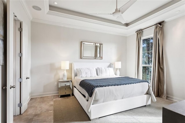 bedroom featuring a ceiling fan, a tray ceiling, crown molding, and baseboards