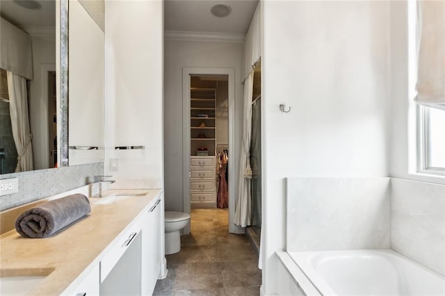 bathroom with a walk in closet, toilet, a garden tub, double vanity, and a sink