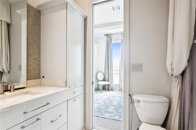 bathroom with vanity, toilet, and visible vents