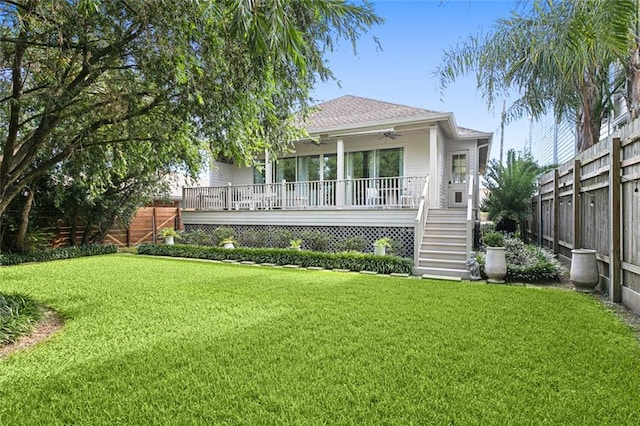 back of property featuring stairway, a lawn, a wooden deck, and fence