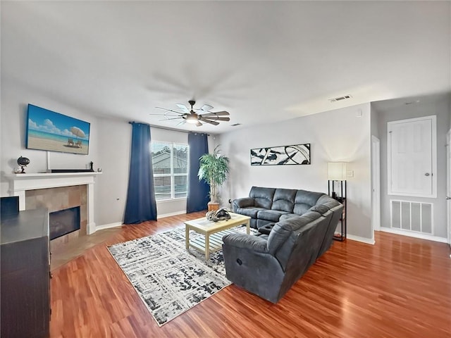 living room with baseboards, a fireplace, visible vents, and wood finished floors