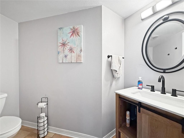 bathroom with a textured ceiling, tile patterned flooring, toilet, vanity, and baseboards