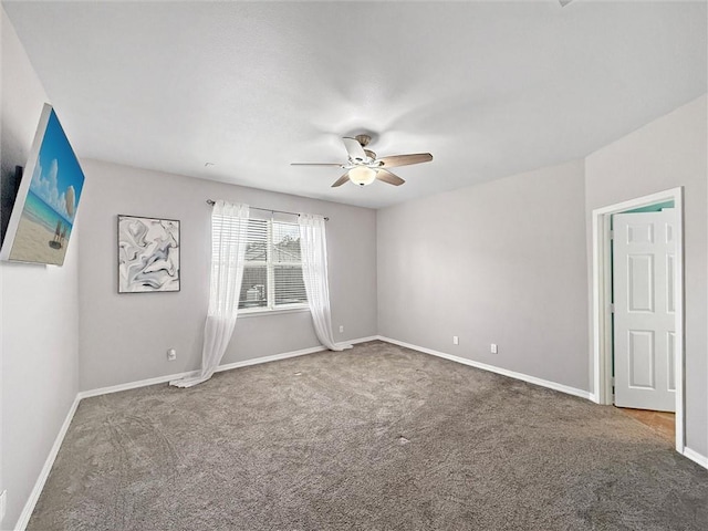 carpeted spare room with a ceiling fan and baseboards