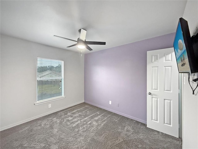 carpeted spare room with a ceiling fan and baseboards