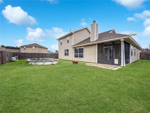 back of house featuring a fenced in pool, a sunroom, a fenced backyard, a chimney, and a yard