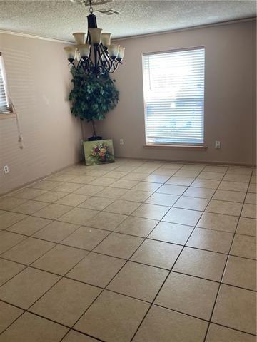 unfurnished dining area featuring ornamental molding, a notable chandelier, a textured ceiling, and light tile patterned floors