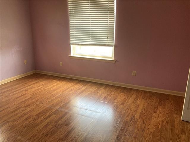 spare room featuring wood finished floors and baseboards