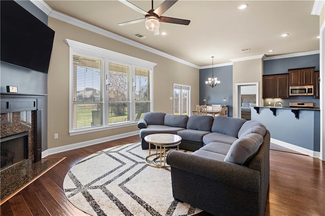 living area with baseboards, visible vents, dark wood-style floors, crown molding, and a high end fireplace