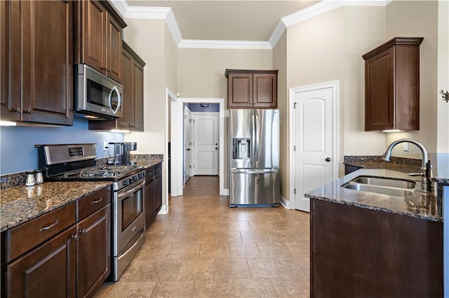 kitchen featuring stainless steel appliances, dark brown cabinets, dark stone countertops, and a sink