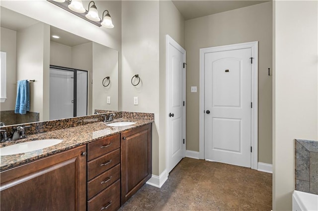 full bath with double vanity, baseboards, and a sink