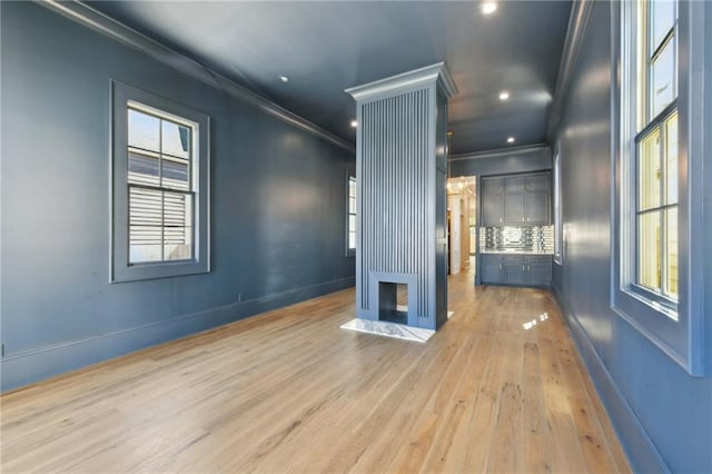 empty room featuring plenty of natural light, crown molding, baseboards, and wood finished floors