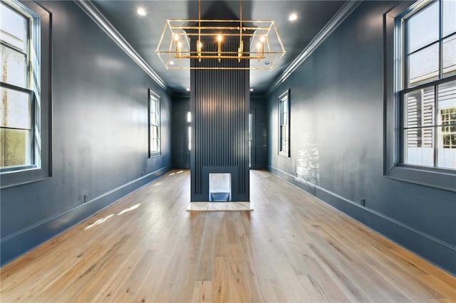 unfurnished room featuring a chandelier, ornamental molding, wood finished floors, and baseboards