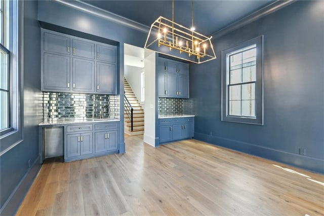 3324 Camp St, New Orleans, LA 70115 - kitchen with ornamental molding, light countertops, a chandelier, tasteful backsplash, and light wood-style floors