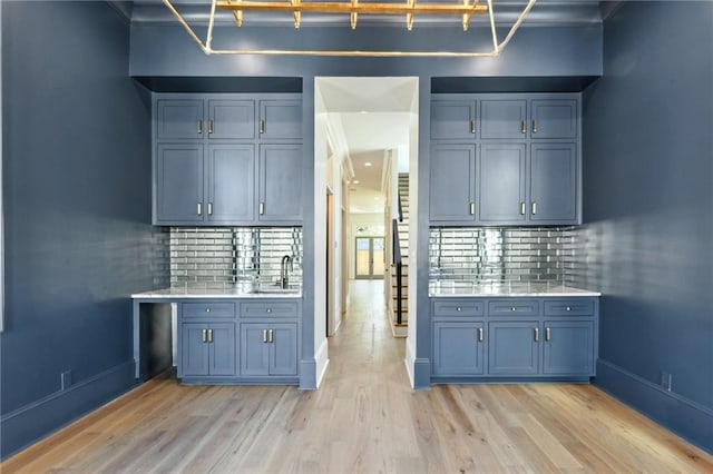 kitchen featuring light wood-style flooring, light countertops, backsplash, and baseboards