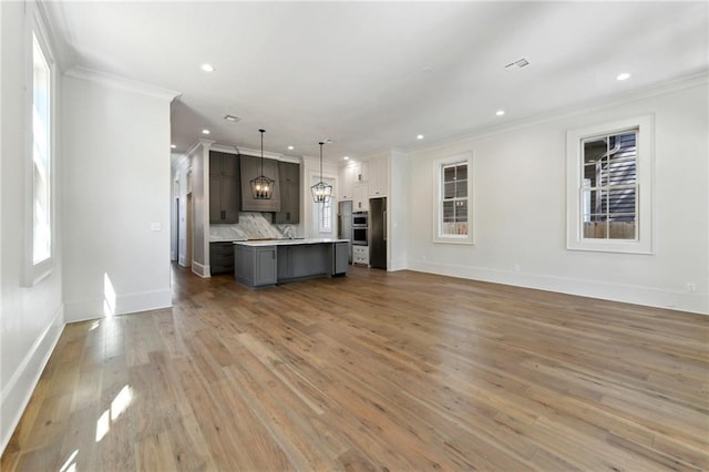 unfurnished living room with baseboards, light wood finished floors, recessed lighting, and crown molding