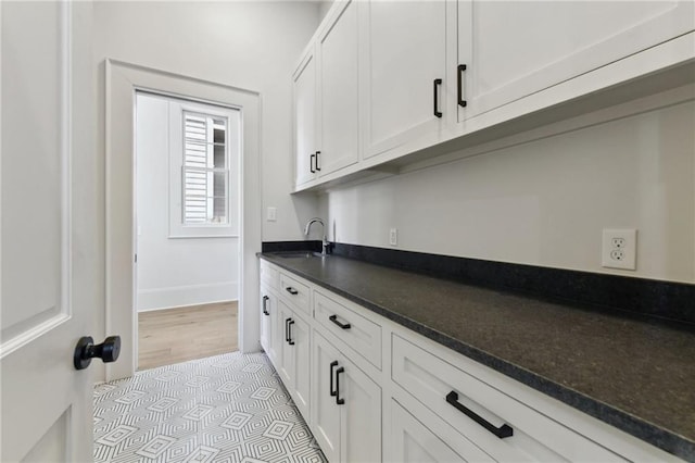3324 Camp St, New Orleans, LA 70115 - kitchen with a sink, dark countertops, white cabinetry, baseboards, and light tile patterned floors