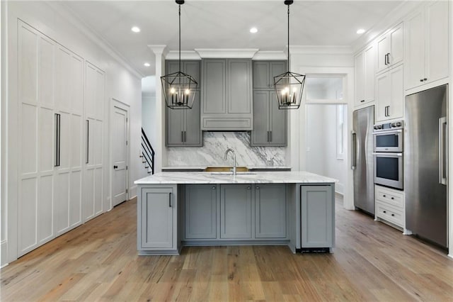 kitchen featuring stainless steel appliances, gray cabinets, backsplash, an inviting chandelier, and a sink