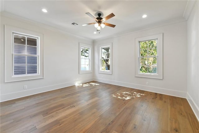 empty room featuring ornamental molding, visible vents, plenty of natural light, and hardwood / wood-style floors