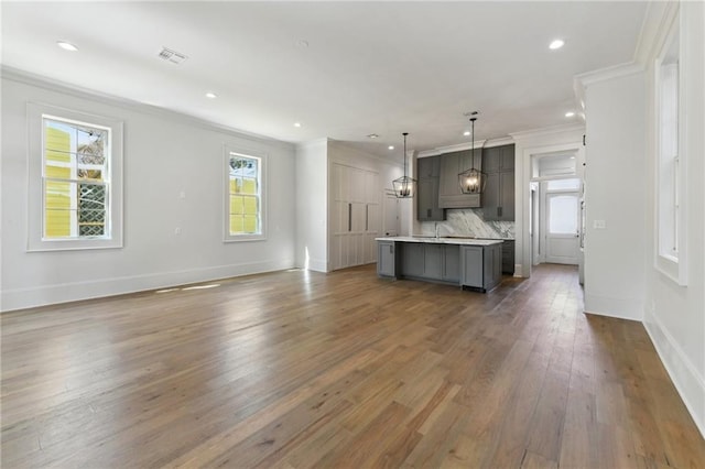 3324 Camp St, New Orleans, LA 70115 - unfurnished living room with crown molding, wood finished floors, baseboards, recessed lighting, and a chandelier