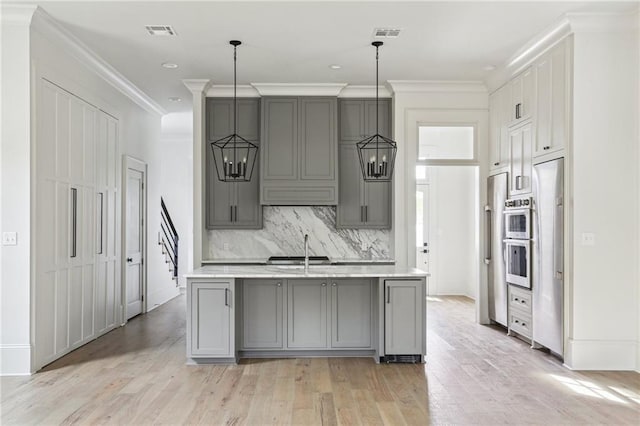 3324 Camp St, New Orleans, LA 70115 - kitchen with gray cabinets, light wood finished floors, backsplash, crown molding, and an island with sink