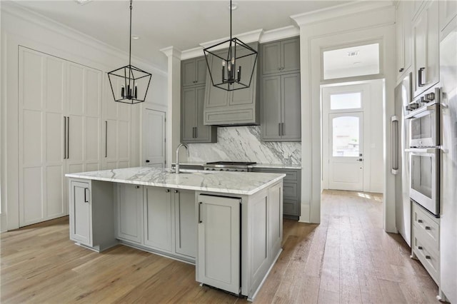 3324 Camp St, New Orleans, LA 70115 - kitchen with gray cabinets, stainless steel double oven, light wood-style floors, and crown molding