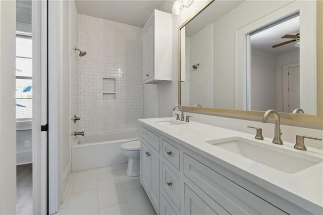 full bathroom with double vanity, a sink, toilet, and a ceiling fan