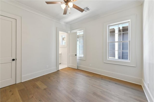 unfurnished room featuring crown molding, visible vents, ceiling fan, wood finished floors, and baseboards