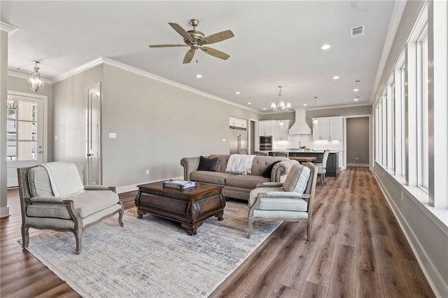 living area featuring recessed lighting, wood finished floors, ceiling fan with notable chandelier, baseboards, and visible vents