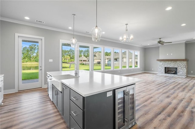 kitchen featuring wine cooler, a fireplace, a sink, visible vents, and light countertops