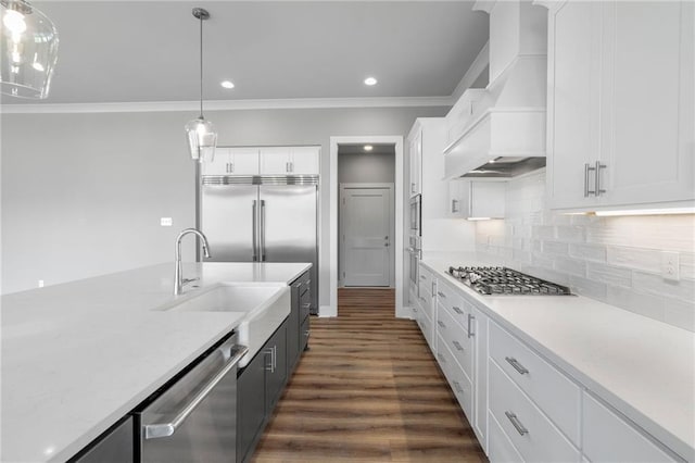 kitchen featuring stainless steel appliances, white cabinets, ornamental molding, decorative backsplash, and custom range hood