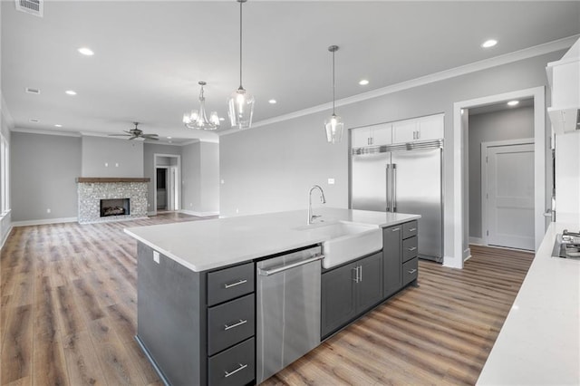 kitchen with a fireplace, light countertops, appliances with stainless steel finishes, a ceiling fan, and white cabinetry