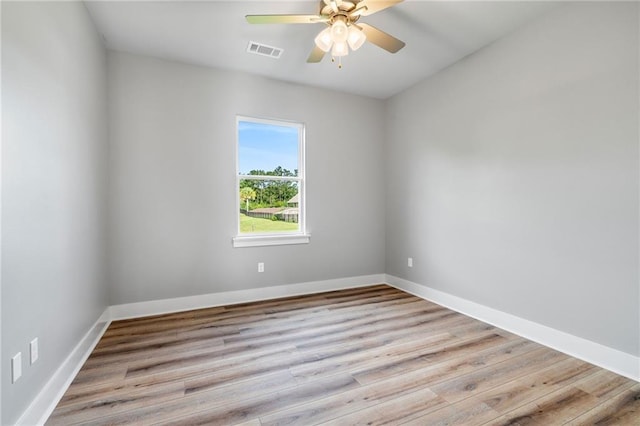 empty room featuring ceiling fan, wood finished floors, visible vents, and baseboards