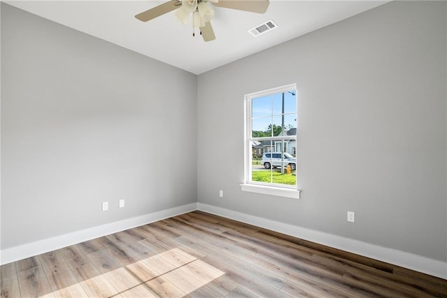 unfurnished room with visible vents, ceiling fan, wood finished floors, and baseboards