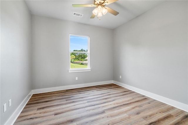 spare room with visible vents, ceiling fan, wood finished floors, and baseboards