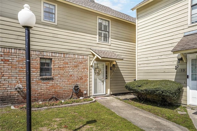 property entrance with brick siding and roof with shingles